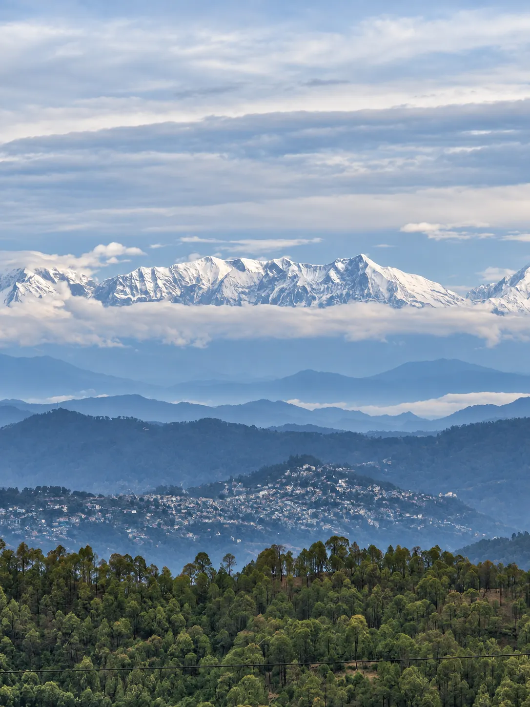 Snow-capped Himalayan peaks above forested hills near Mukteshwar